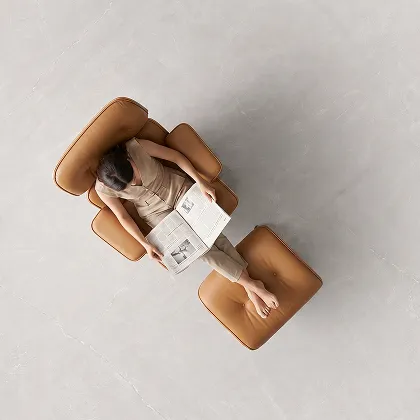 Seen from above, a woman reads in a leather lounge chair on a pale stone-look Letoza floor